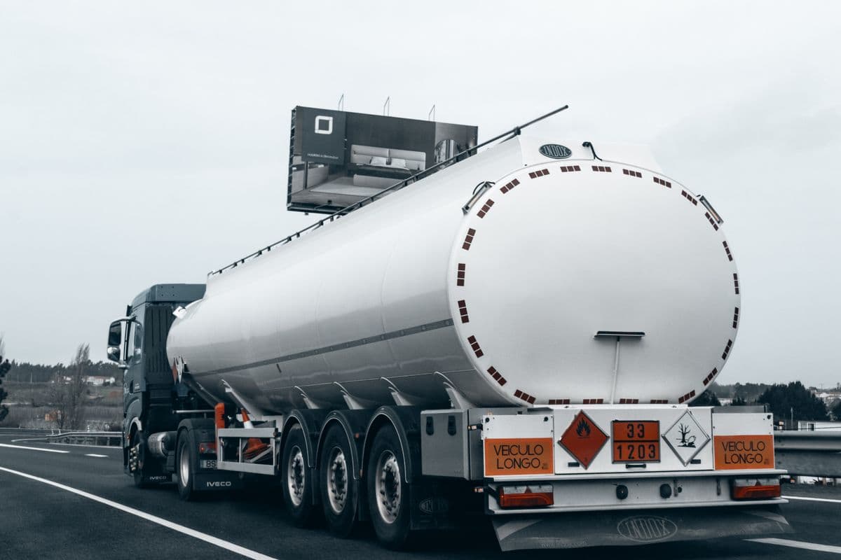 Road tanker on a motorway carrying orange ADR hazard plates and class labels.